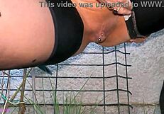 MILF La Gourmande en falda de cuero y medias mea en jardín en primer plano, provocando su clítoris perforado