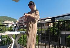 Nackt in der Öffentlichkeit auf dem Balkon über der belebten Straße