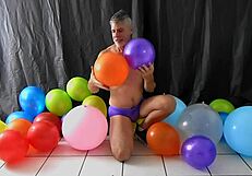 Mature gay DILF Richard Lennox plays with balloons during session