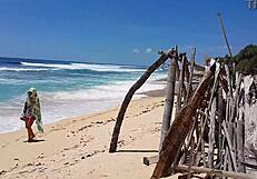 Sandy buttocks on a wonderful beach, with a crimson anal plug