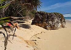 Sandy buttocks on a wonderful beach, with a crimson anal plug