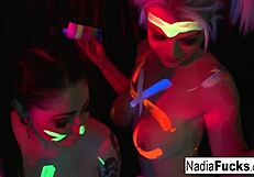 Black-light babes suck off a colorful cock in a threesome
