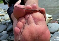 goddess teases with tan nylon soles and toes by the riverside, close-up fetish delight