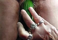 granny teases her hairy old pussy with a thick cucumber insertion