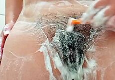 check out this young brunette shaving her hairy pussy up close in the bathroom mirror