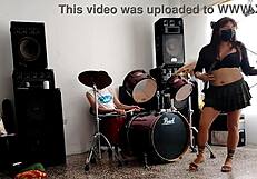They play drums while she dances stripping and shaking her ass