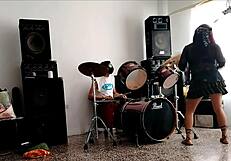 They play drums while she dances stripping and shaking her ass