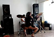 They play drums while she dances stripping and shaking her ass