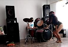 They play drums while she dances stripping and shaking her ass