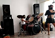 They play drums while she dances stripping and shaking her ass