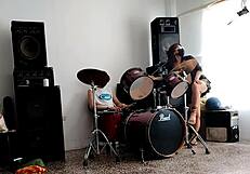 They play drums while she dances stripping and shaking her ass